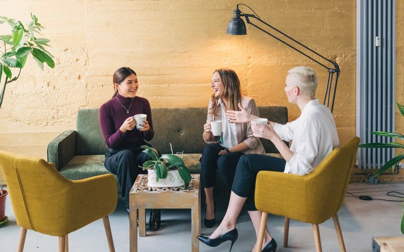 3 Frauen sitzen in einer Lounge Ecke und führen ein fröhliches Gespräch zum Thema HR-Assessment