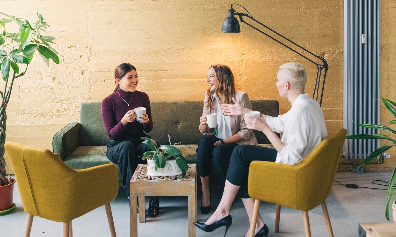 Drei Frauen sitzen in Loungebereich und unterhalten sich über HR Assessment bei einem Kaffee